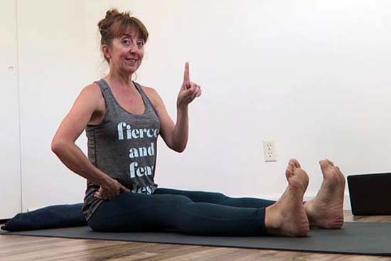yoga teacher sitting in dandasana with feet apart