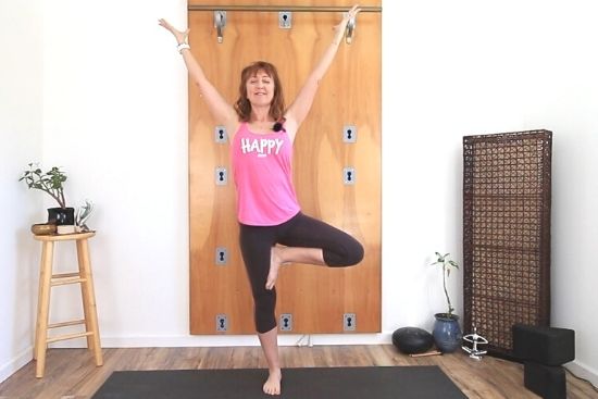 tree pose with arms lifted and eyes closed