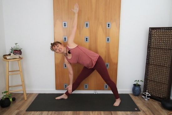 yoga teacher demonstrating triangle pose at the wall
